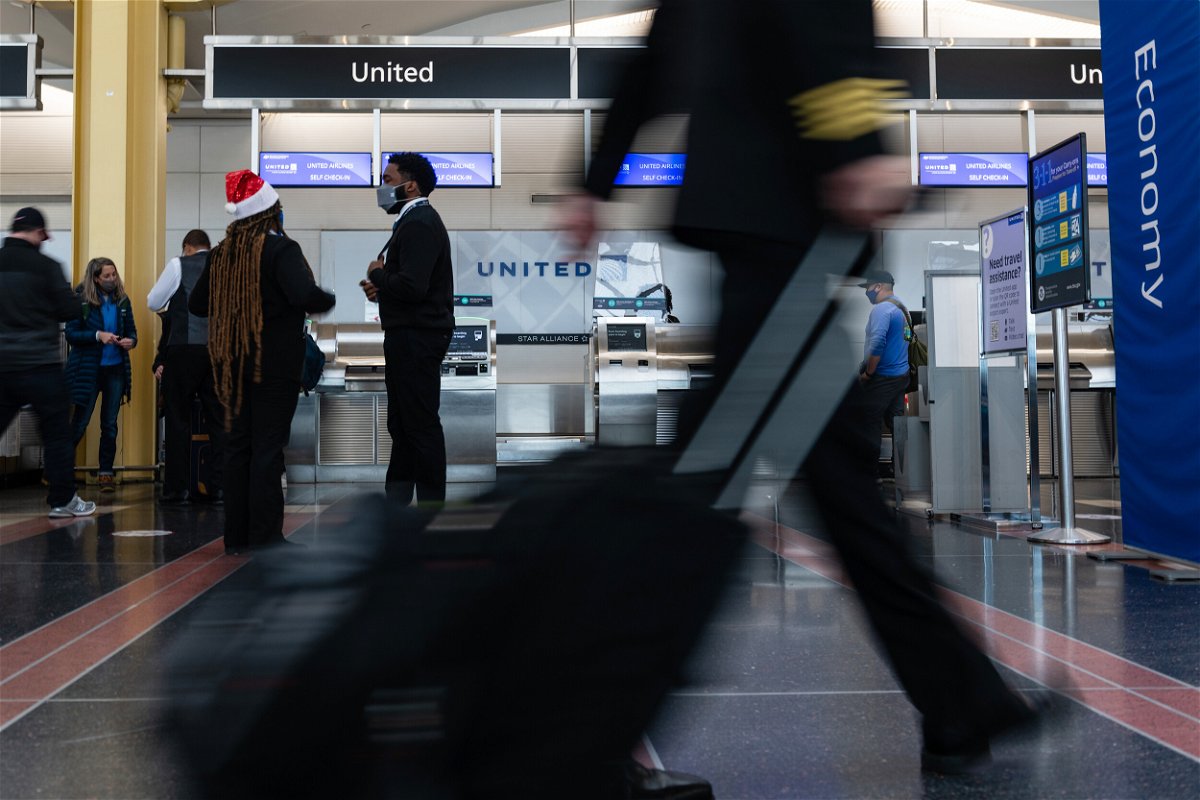 <i>Bloomberg/Bloomberg/Bloomberg via Getty Images</i><br/>An airline crew member rolls their bag past the United Airlines ticket counter at Reagan National Airport in Arlington