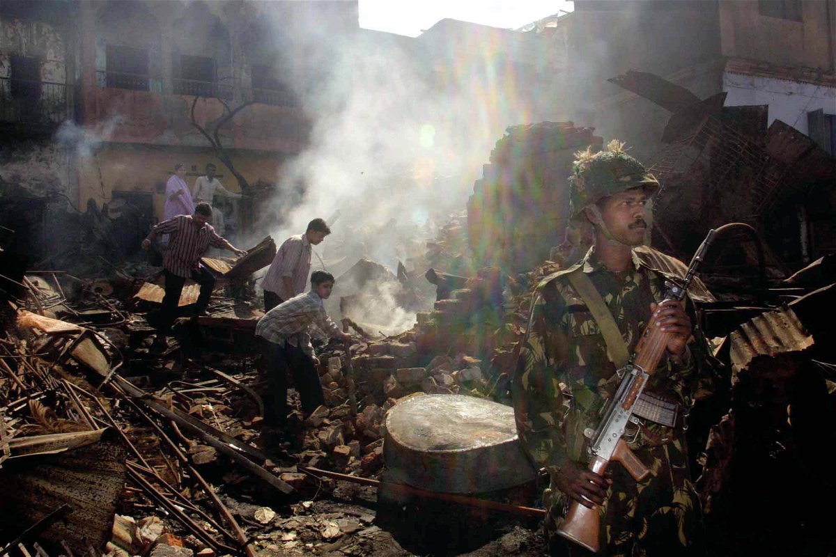 <i>Manish Swarup/AP</i><br/>An Indian Muslim family looks for valuables from their burned home while an Indian army soldier stands guard in the downtown area of Ahmedabad