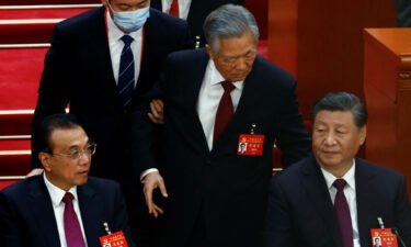 Former Chinese leader Hu Jintao leaves his seat next to leader Xi Jinping and Premier Li Keqiang