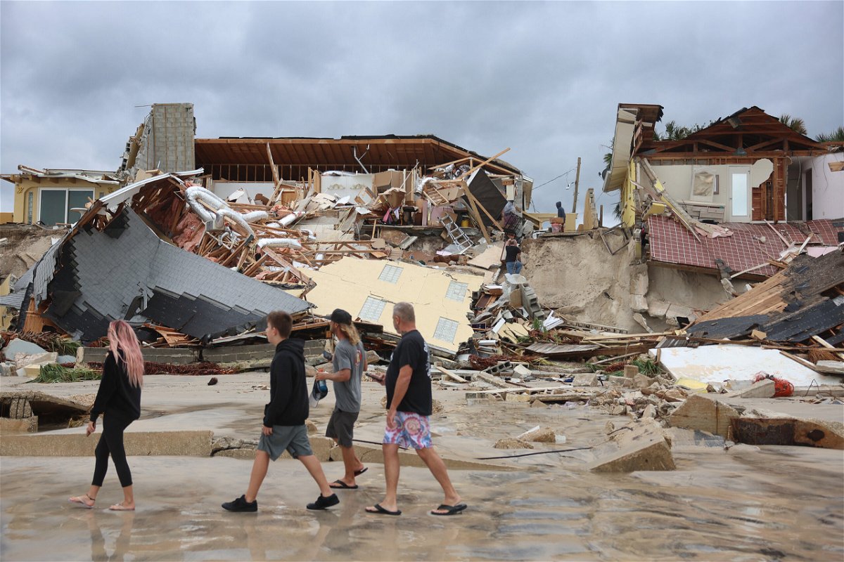 <i>Joe Raedle/Getty Images</i><br/>People look on at homes partially toppled onto the beach after Hurricane Nicole came ashore on November 10 in Daytona Beach