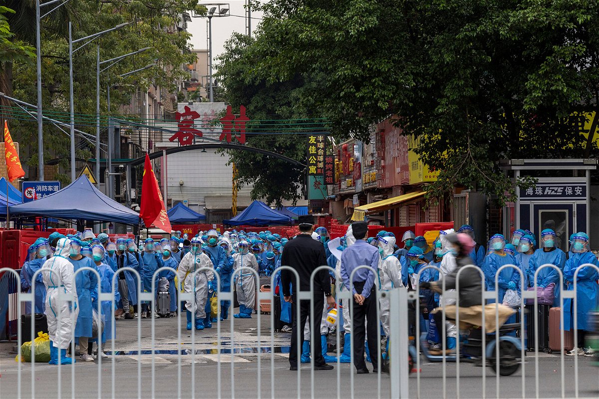<i>Chinatopix/AP</i><br/>Law enforcers wearing white hazmat suits prepare to transfer residents in blue protective clothing at a high-risk neighborhood in Guangzhou on November 5.