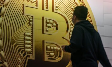 Pedestrians walk past an advertisement displaying a Bitcoin cryptocurrency token in February in Hong Kong.