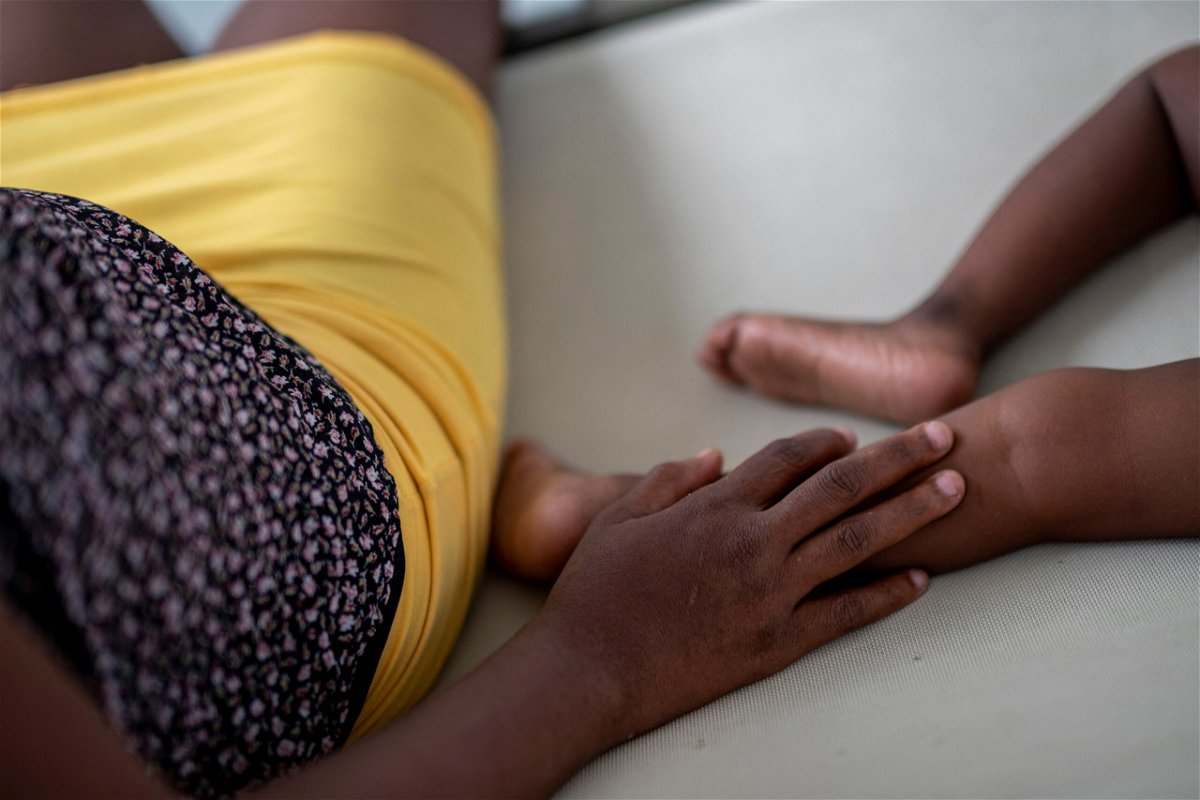 A woman sits next to a child as he receives treatment for cholera at the Gheskio Center Hospital supported by UNICEF in Port-au-Prince
