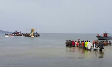 Rescuers in boats and standing in the water are seen around the tail fin of a crashed Precision Air passenger aircraft on the shores of Lake Victoria in Bukoba