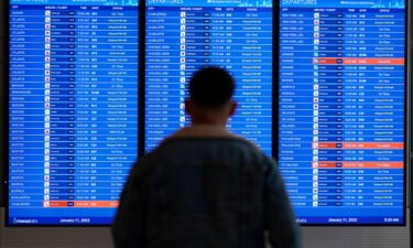 A traveler looks at a flight board with delays and cancellations at Ronald Reagan Washington National Airport in Arlington