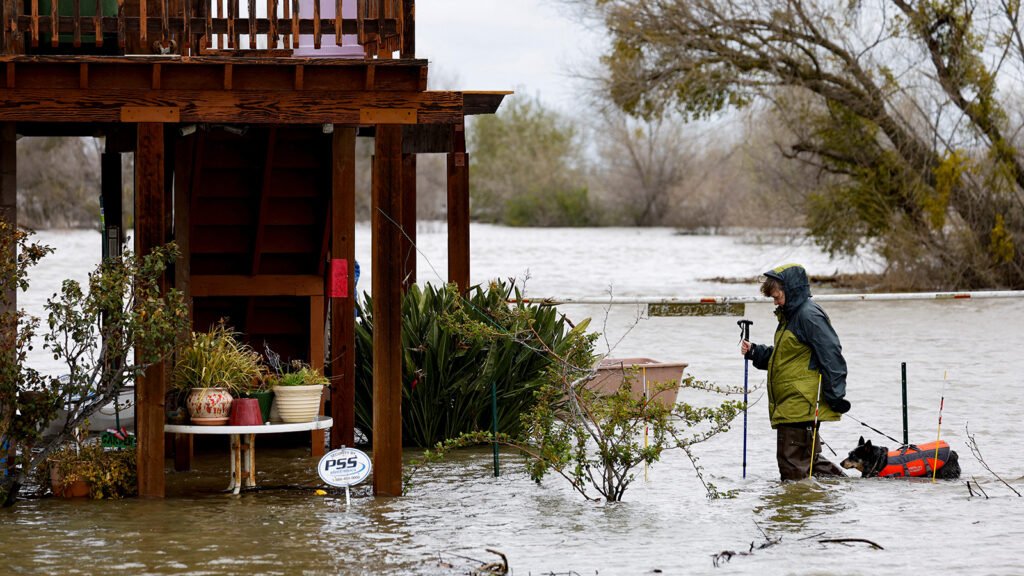 Kristen Vogt and her dog Roo walk through floodwaters to go back to their house, after the flooding of the San Joaquin River, in Manteca, California, U.S. March 19, 2023.  REUTERS/Fred Greaves