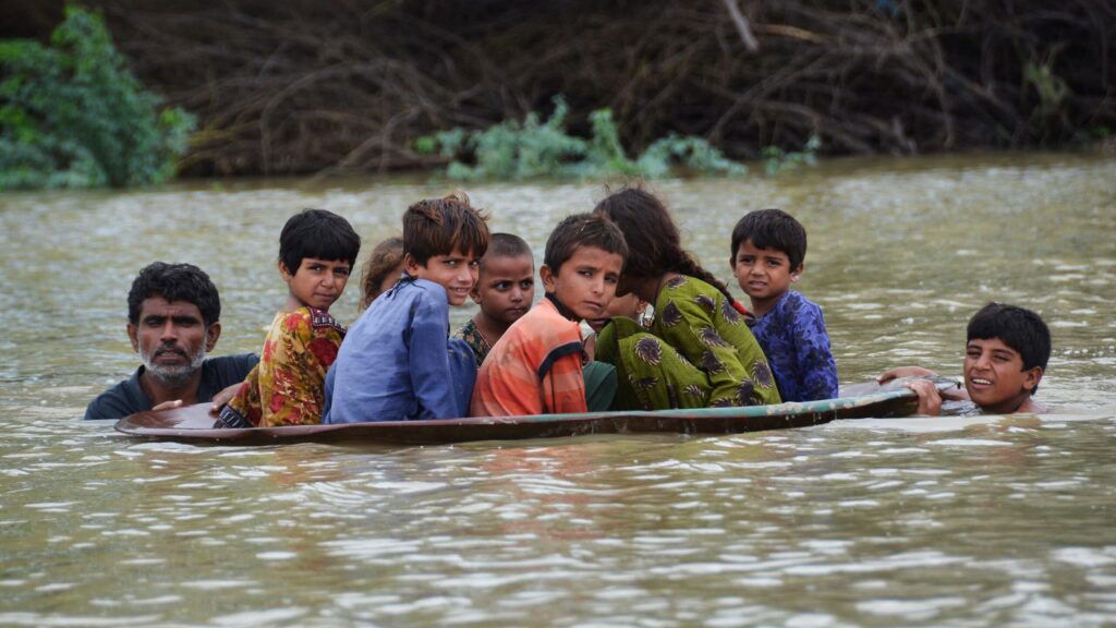 TOPSHOT - A man (L) along with a youth use a satellite dish to move children across a flooded area after heavy monsoon rainfalls in Jaffarabad district, Balochistan province, on August 26, 2022. - Heavy rain continued to pound parts of Pakistan on August 26 after the government declared an emergency to deal with monsoon flooding it said had 