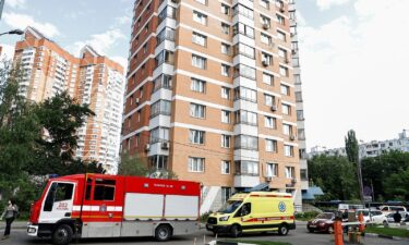 An ambulance and firefighting vehicles are parked outside a multi-storey apartment block following a reported drone attack in Moscow