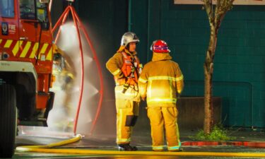 Firefighters stand outside the hostel where a fire broke out overnight.