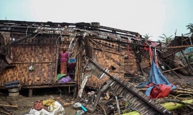 A Rohingya woman stands in her damaged house at Basara refugee camp in Sittwe on May 16 following Cyclone Mocha.