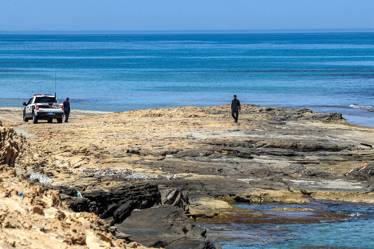 <i>Mahmud Turkia/AFP/Getty Images</i><br/>Security personnel wait by a police vehicle along the Mediterranean shoreline near Qarabulli