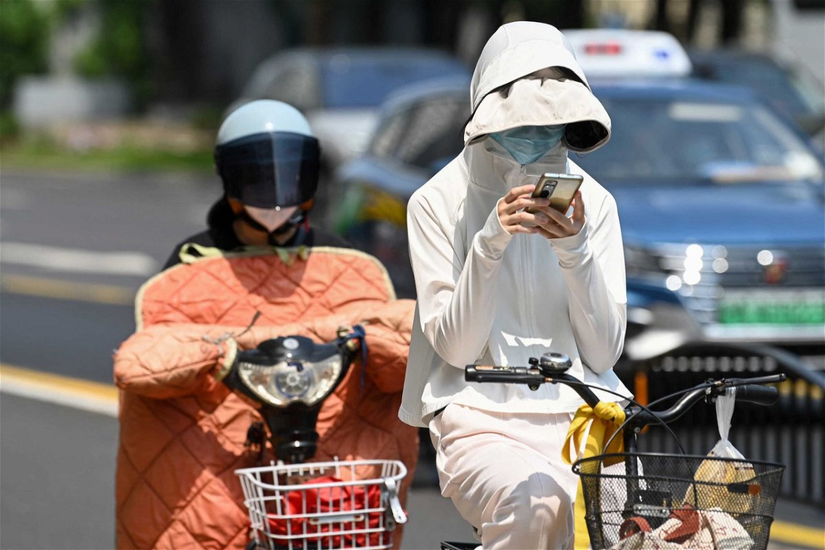 <i>Stringer/AFP/Getty Images</i><br/>A woman wearing sun protective clothing commutes on a bicycle amid hot weather in Shanghai on Monday.