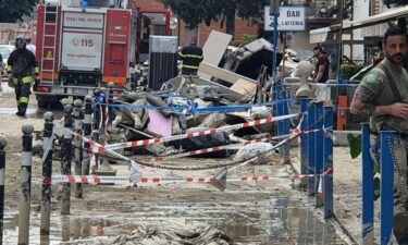 Firefighters help clear debris and mud from a street in Forli