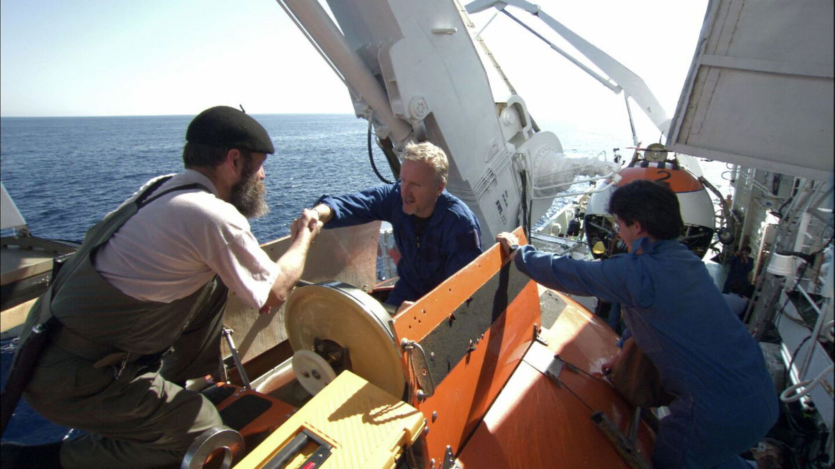 MIR crew members help James Cameron (center) into MIR 1 during the filming of Cameron's documentary 