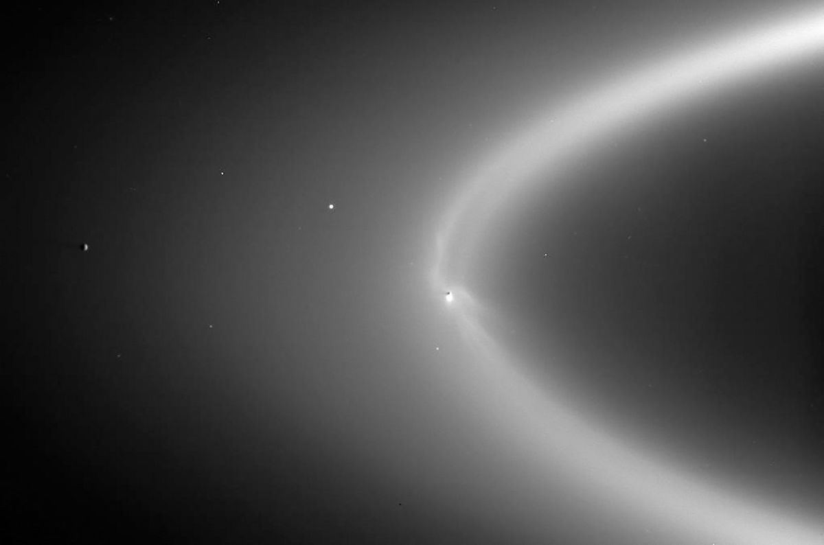 <i>NASA/JPL/Space Science Institute</i><br/>Wispy arcs of icy material expand out from Enceladus (brightest white dot above) into Saturn's E ring.