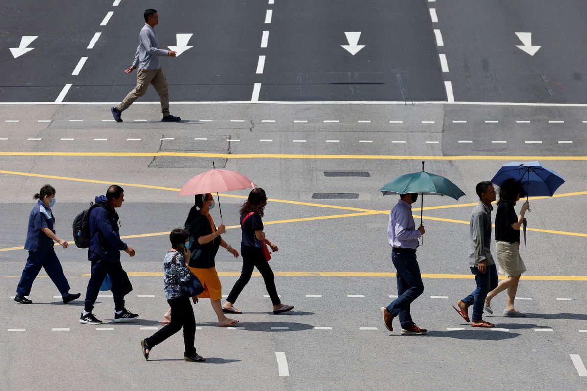 <i>Edgar Su/Reuters</i><br/>People in Singapore shield themselves with umbrellas from the glaring sun as they cross a street.