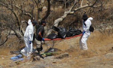 Forensic experts carry bags of human remains found in a ravine in Zapopan