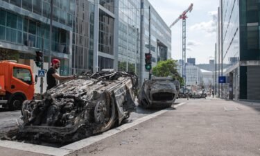 Workers clear a street filled with charred cars in Nanterre