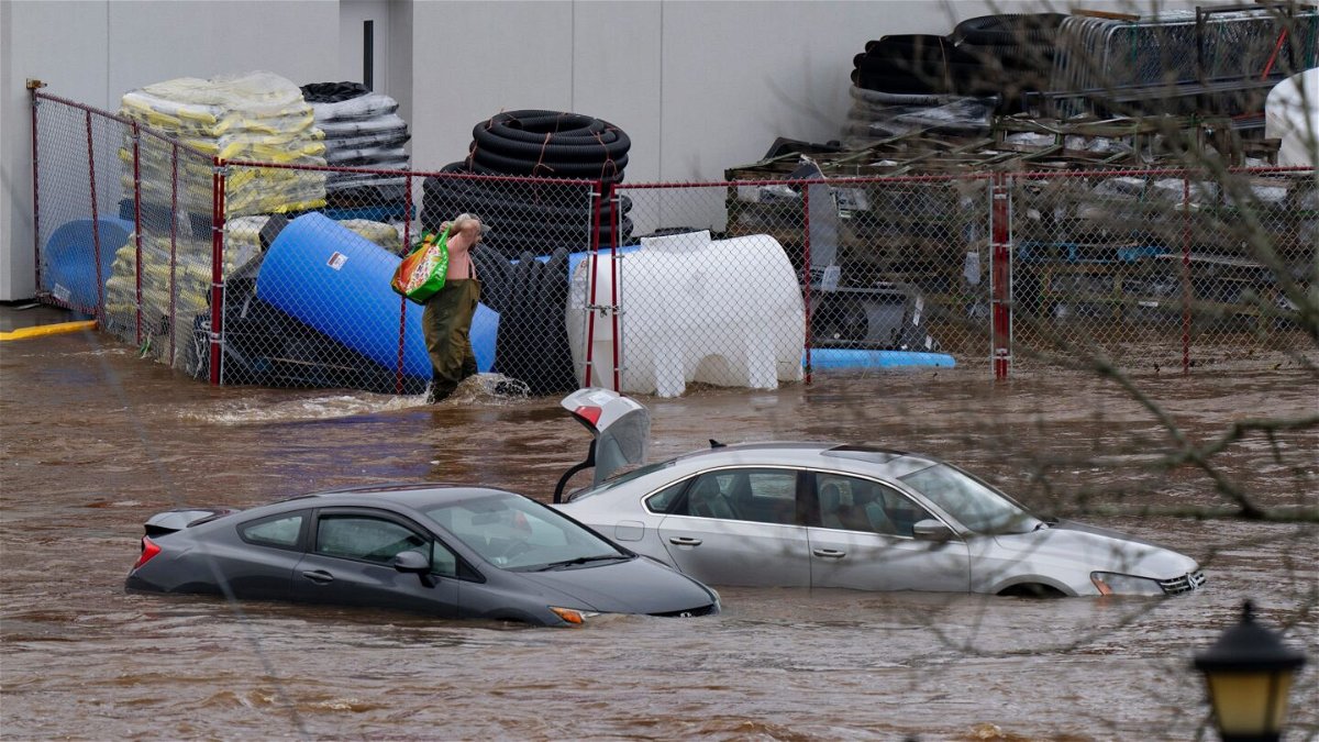 <i>Darren Calabrese/The Canadian Press/AP</i><br/>A man wearing chest waders walks past cars abandoned in floodwaters in a mall parking lot in Halifax