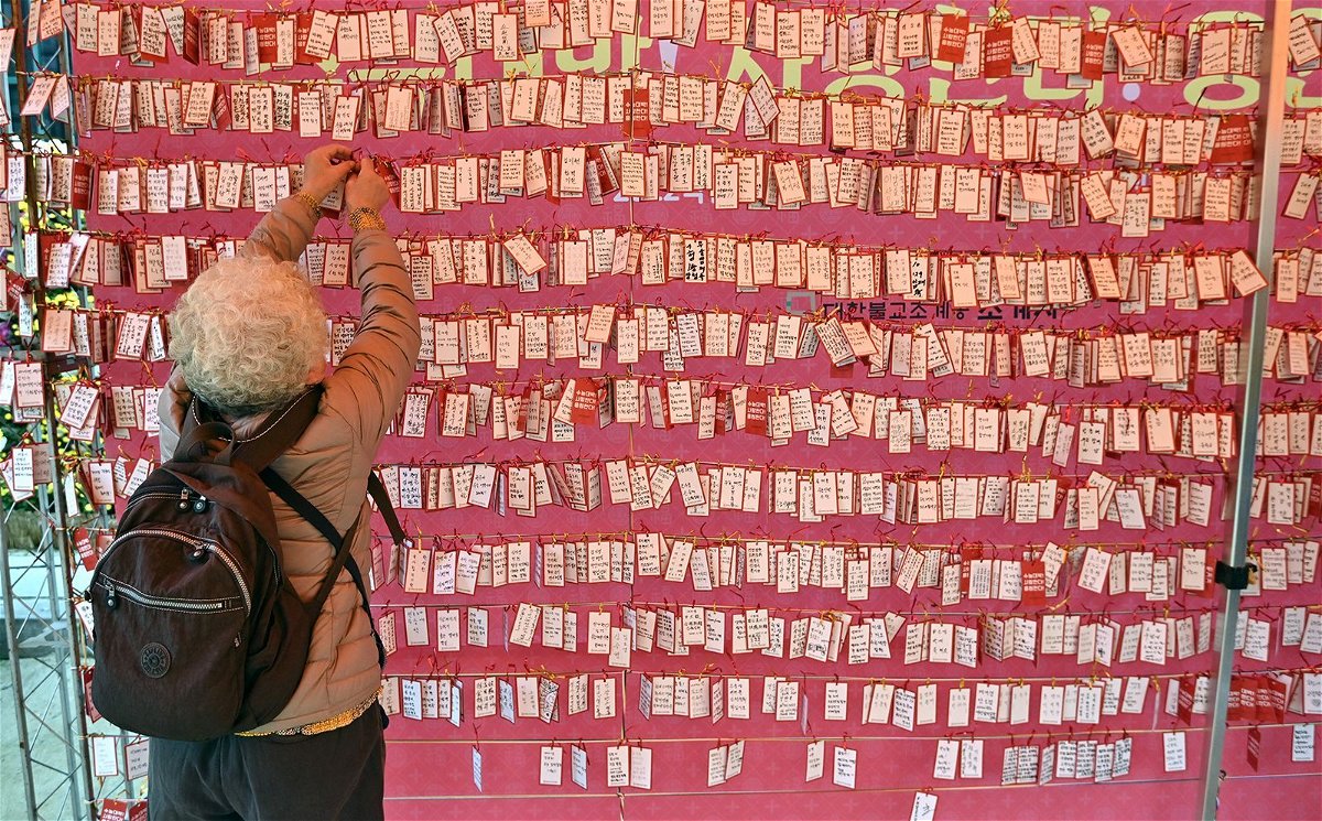 <i>Jung Yeon-je/AFP/Getty Images/File</i><br/>A woman attaches a name card wishing for good results for students in South Korea's college entrance exam