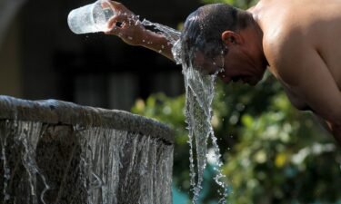 A man cools himself down with water from a water fountain during one of the hottest days of the third heat wave in Guadalajara