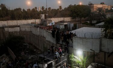 Protesters climb a fence near the Swedish embassy in Baghdad on July 20.