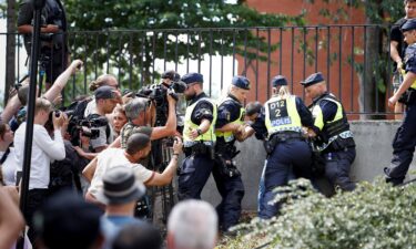 Police officers seen as demonstrators burn the Quran outside Stockholm's central mosque in Stockholm