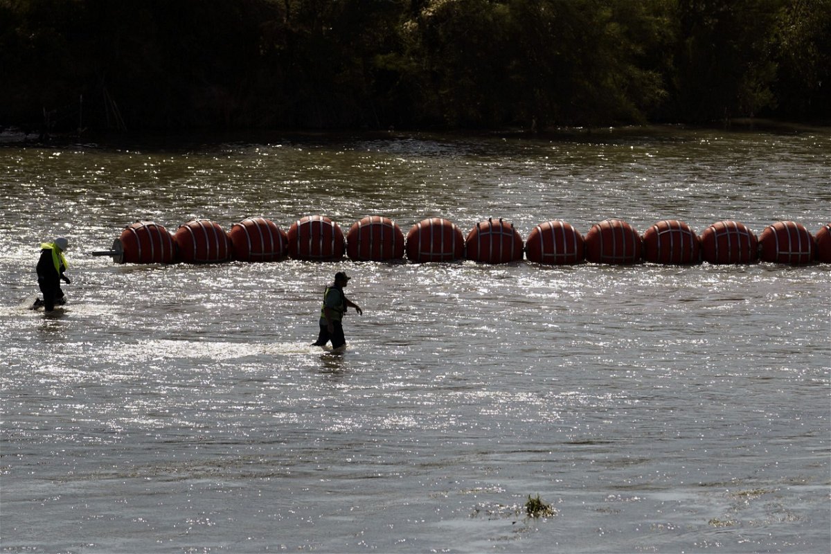 Workers help deploy a string of large buoys to be used as a border barrier at the center of the Rio Grande near Eagle Pass, Texas, July 11. The floating barrier is being deployed in an effort to block migrants from entering Texas from Mexico.