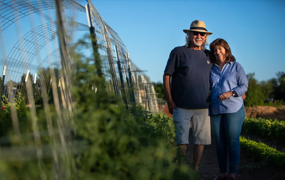 Ralph and Marty Loya, owners of Growing With Sara farm, stand among rows of produce.