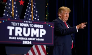 Former President Donald Trump greets supporters as he arrives at a commit to caucus rally