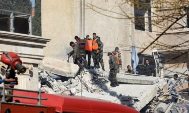 Security and emergency personnel search the rubble of a building destroyed in Damascus
