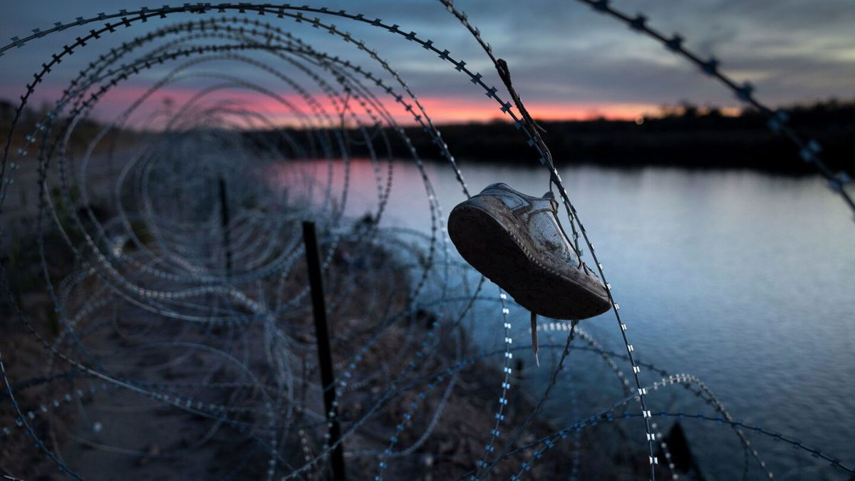 A child's shoe hangs caught in razor wire atop the bank of the Rio Grande on January 9, in Eagle Pass, Texas. Following a major surge of migrant border crossings late last year, large quantities of refuse left behind by migrants as well as miles of razor wire installed by Texas National Guard troops remain along the U.S.-Mexico border at Eagle Pass.