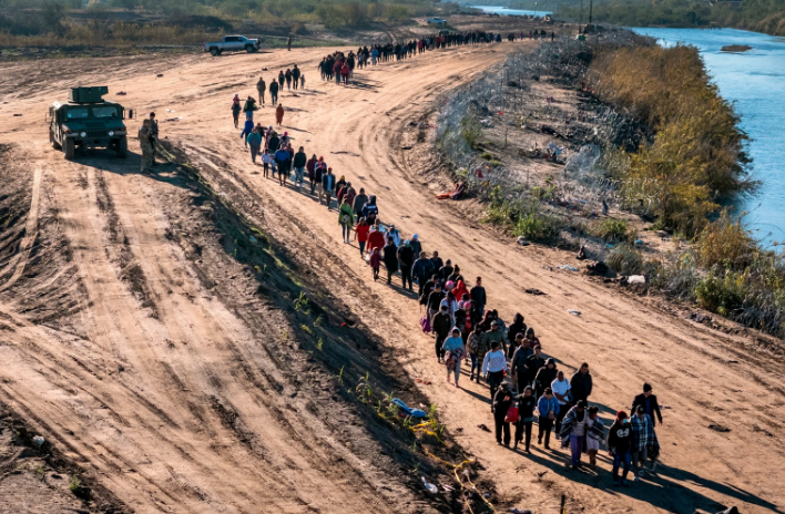 In this aerial view, a group of more than 1,000 immigrants walks towards a U.S. Border Patrol field processing center after they crossed the Rio Grande from Mexico, on Dec. 18, 2023, in Eagle Pass, Texas.