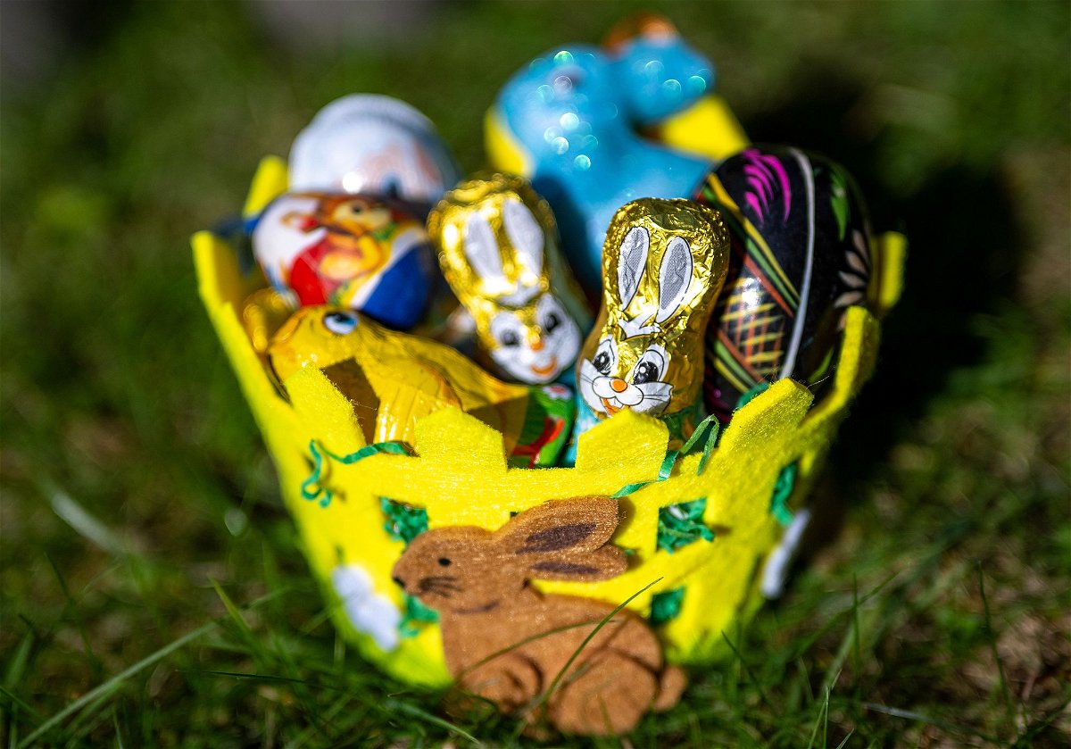 An Easter basket filled with chocolate figures and decorative eggs sits in a garden on March 18