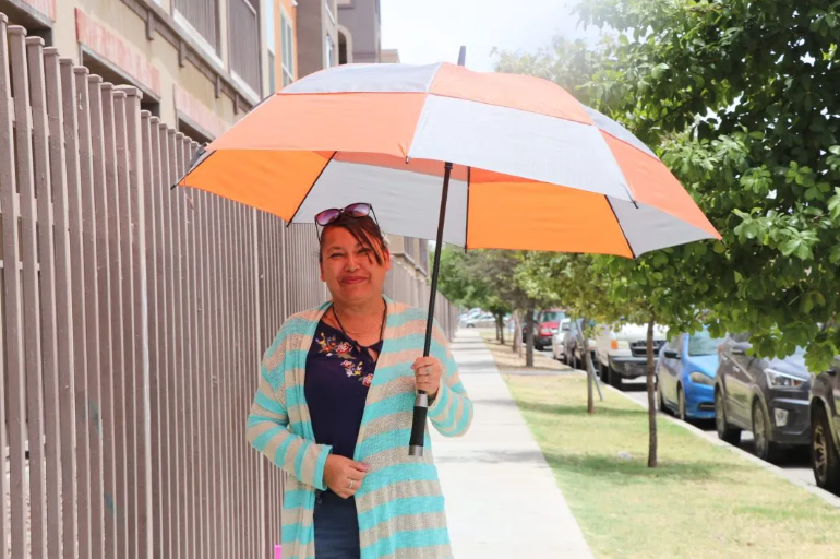 Victoria Paez shades herself from 90-plus degree heat while walking through the Chamizal neighborhood on the morning of June 4.