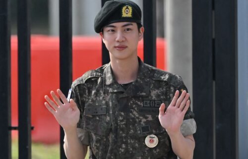 K-pop boy band BTS member Jin waves after being discharged from his mandatory military service outside a military base in Yeoncheon