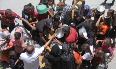 Palestinians gather to receive food cooked by a charity kitchen in Jabalia refugee camp