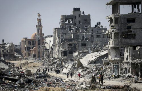 People walk amid the rubble of buildings destroyed during Israeli bombardment in Khan Younis