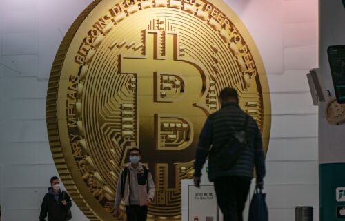 Pedestrians walk past an advertisement displaying a Bitcoin cryptocurrency token in February 2022 in Hong Kong