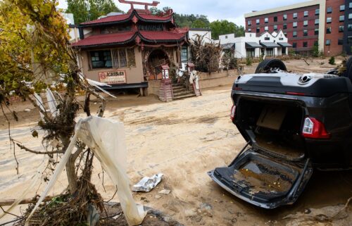 A sign commemorating the flood of 1916 lies on the ground next to a flooded waterway near Biltmore Village.